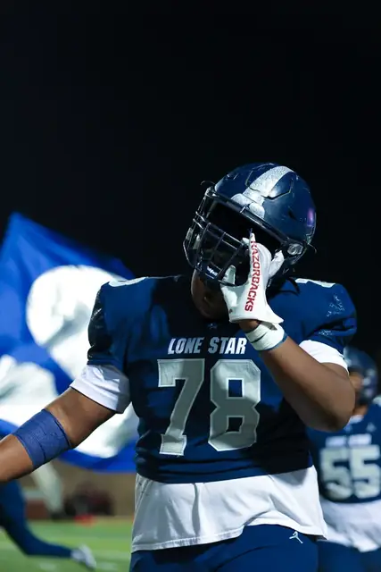 Lone Star football player number 18 in a navy jersey under stadium lights