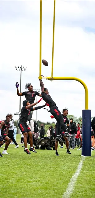 Football athletes jumping together beneath a yellow goalpost