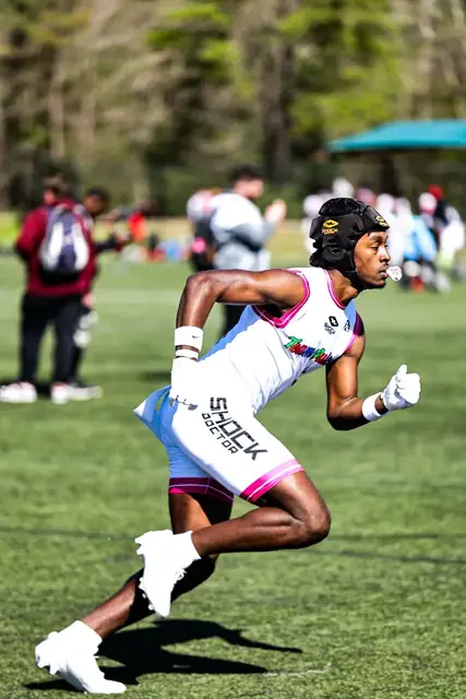 Football athlete accelerating across a grass field during a seven-on-seven game