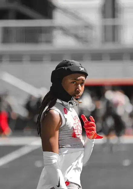 Athlete in a white uniform and black padded headguard looking toward the camera