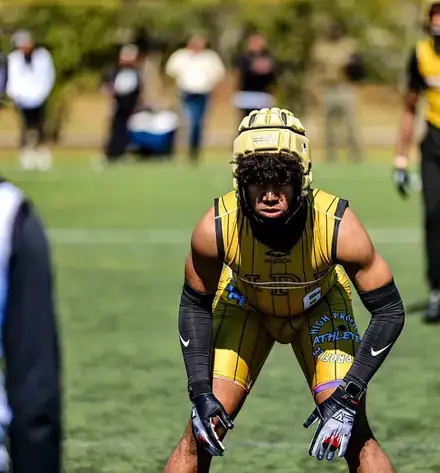 Football athlete in a yellow uniform crouching in a ready stance