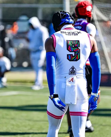 Football player wearing number 9 on a white uniform with bright pink and blue details